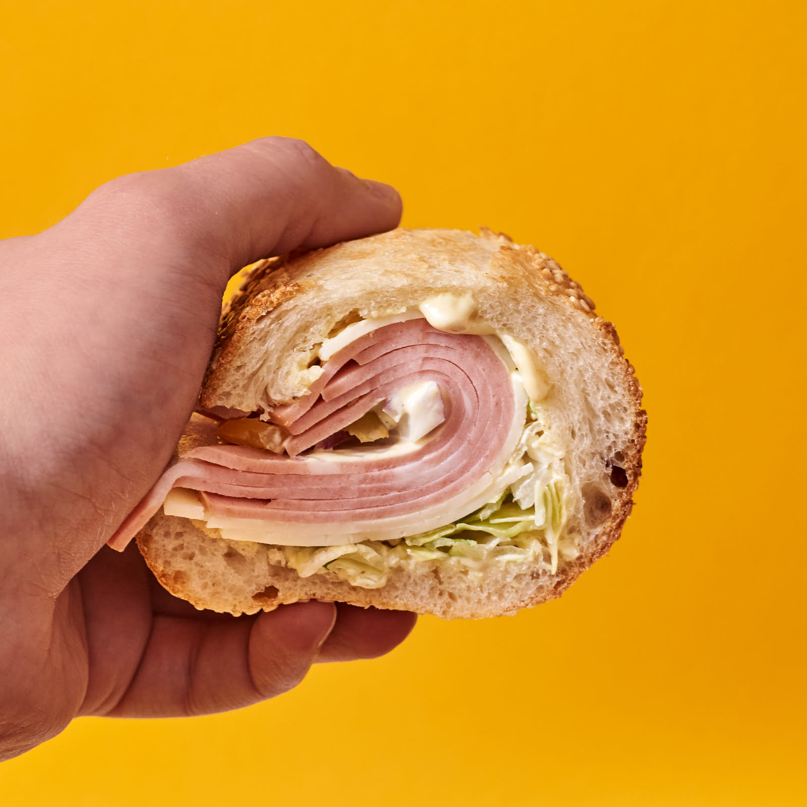 A seeded and scooped-out hoagie roll from this recipe with mortadella, sharp provolone, onion, shrettuce, dijonaise, and pickled hot banana peppers. This mortadella was untenably thick, but this is here to demonstrate the hoagie roll.