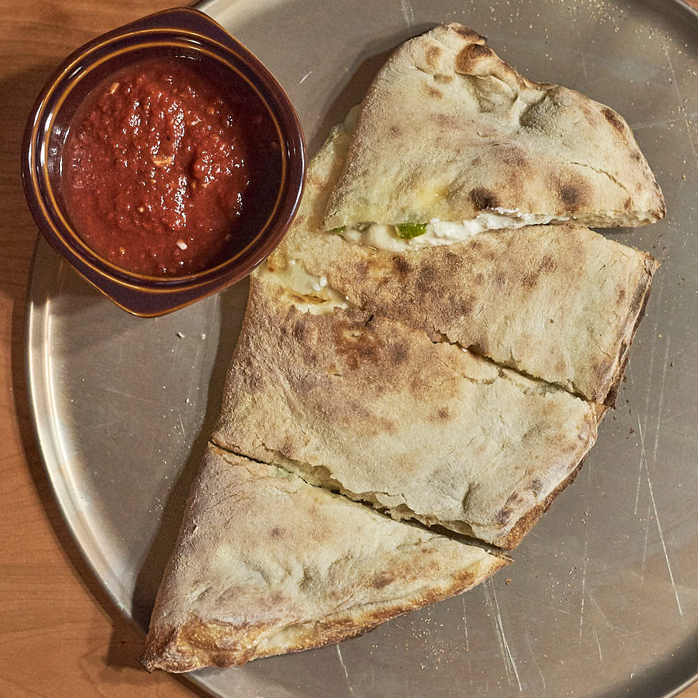 A calzone made from this New York-style pizza dough, filled with aged mozzarella, whole milk ricotta, Pecorino Romano, Parmesan Parmigiano-Reggiano, and Castelvetrano olives. Baked in a typical home oven on a 3/8-inch-thick steel plate.