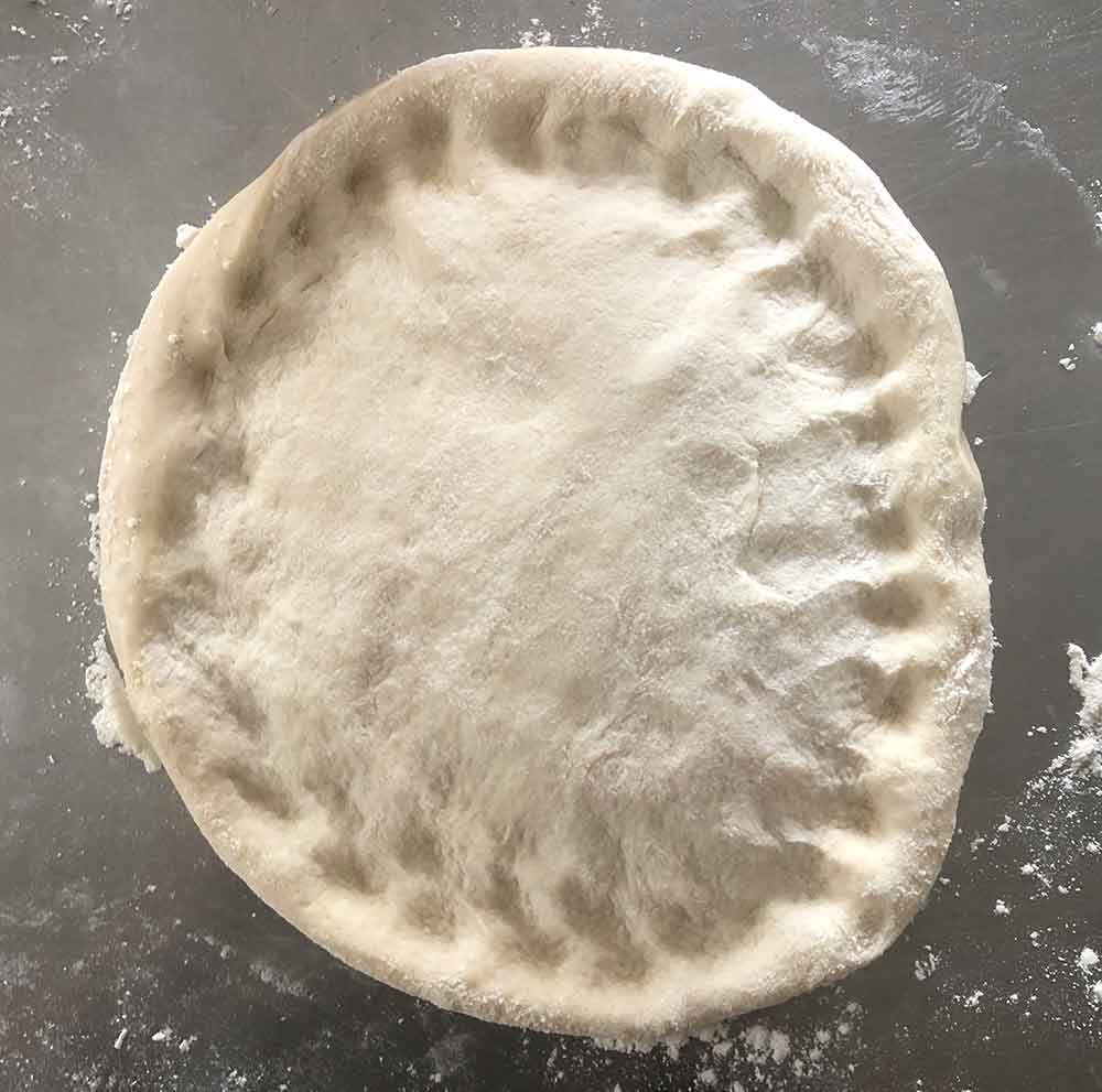 A dough that’s been poked to have a rim area defined.
