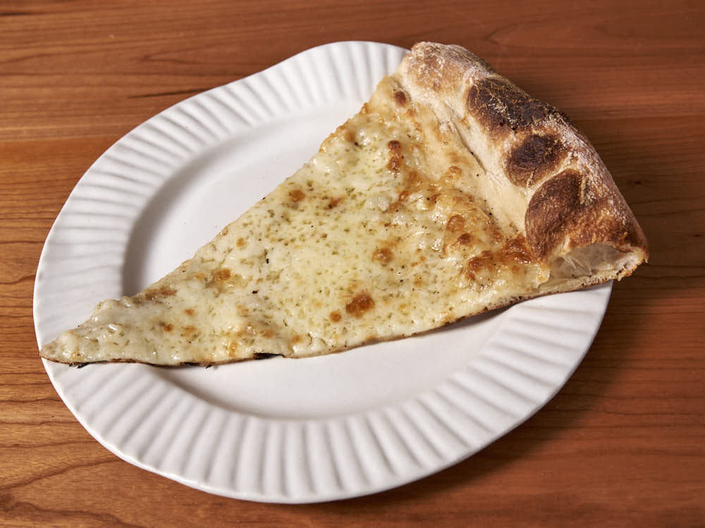 Pizza with aged mozzarella, fresh mozzarella, and Parmesan Reggiano, Pecorino Romano, Tellicherry pepper, and dried oregano. Baked in a commercial deck oven.