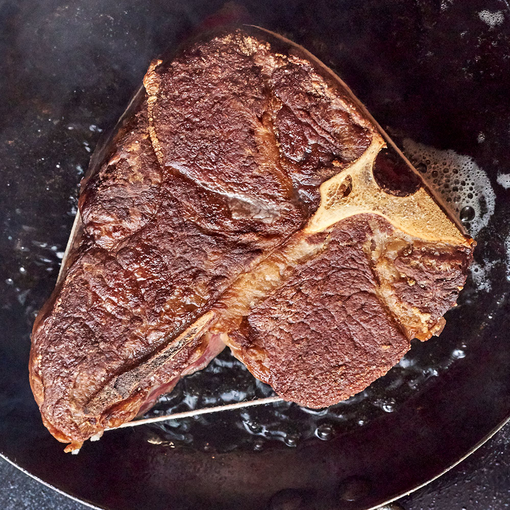 A Lobel’s porterhouse searing in a carbon steel pan.